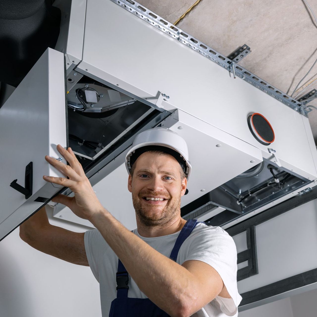 a man is working on a ventilation system in a building .
