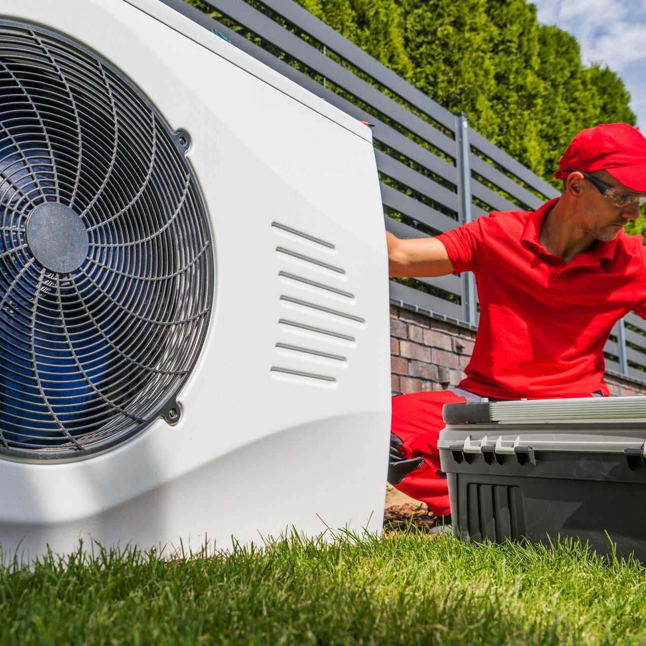 a man in a red shirt is working on a heat pump .