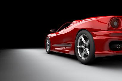 A red sports car is parked on a white surface