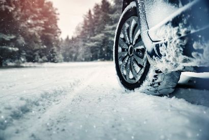 A car is driving through the snow on a snowy road.