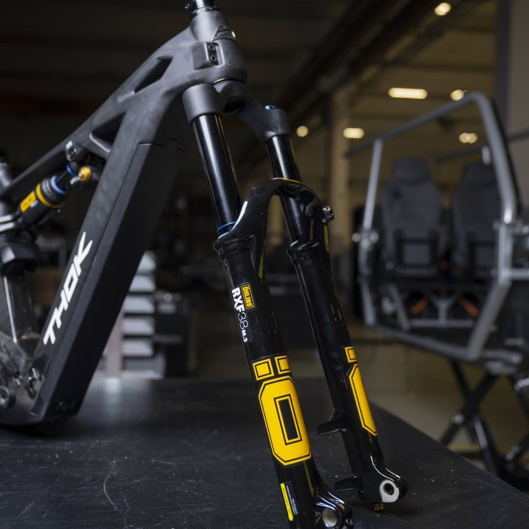 Telaio di mountain bike nero con forcella anteriore ammortizzata gialla in un ambiente da palestra.