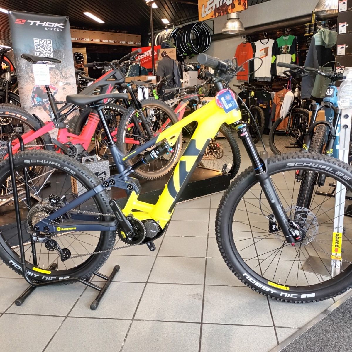 Mountain bike gialla e nera esposta in un negozio di biciclette, con altre biciclette sullo sfondo.