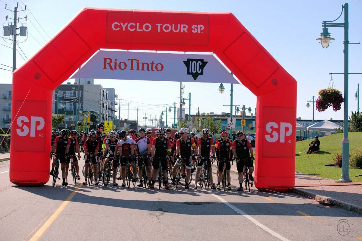 Cyclists under a red inflatable arch, 