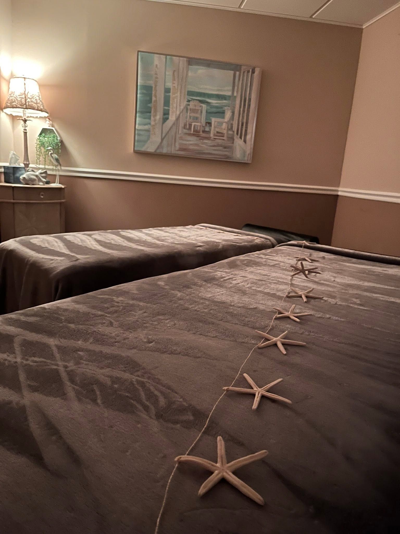 Hotel room with two neatly made beds, a bedside lamp, and a framed abstract painting on the wall