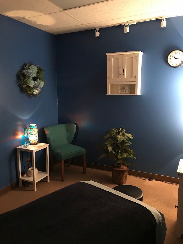 Blue waiting room with a chair, side table, wall clock, plant, and framed wall decor