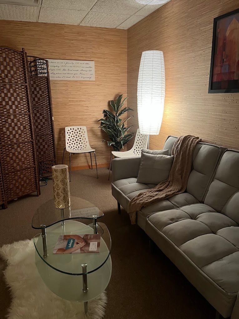 Quiet waiting room with sofa, glass coffee table, chair, lamp, and room divider.