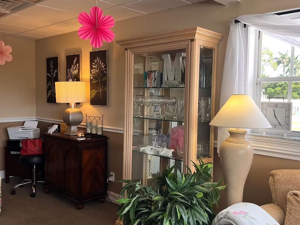 Bright living room with beige sofa, glass cabinet, lamps, desk chair, and pink hanging decoration