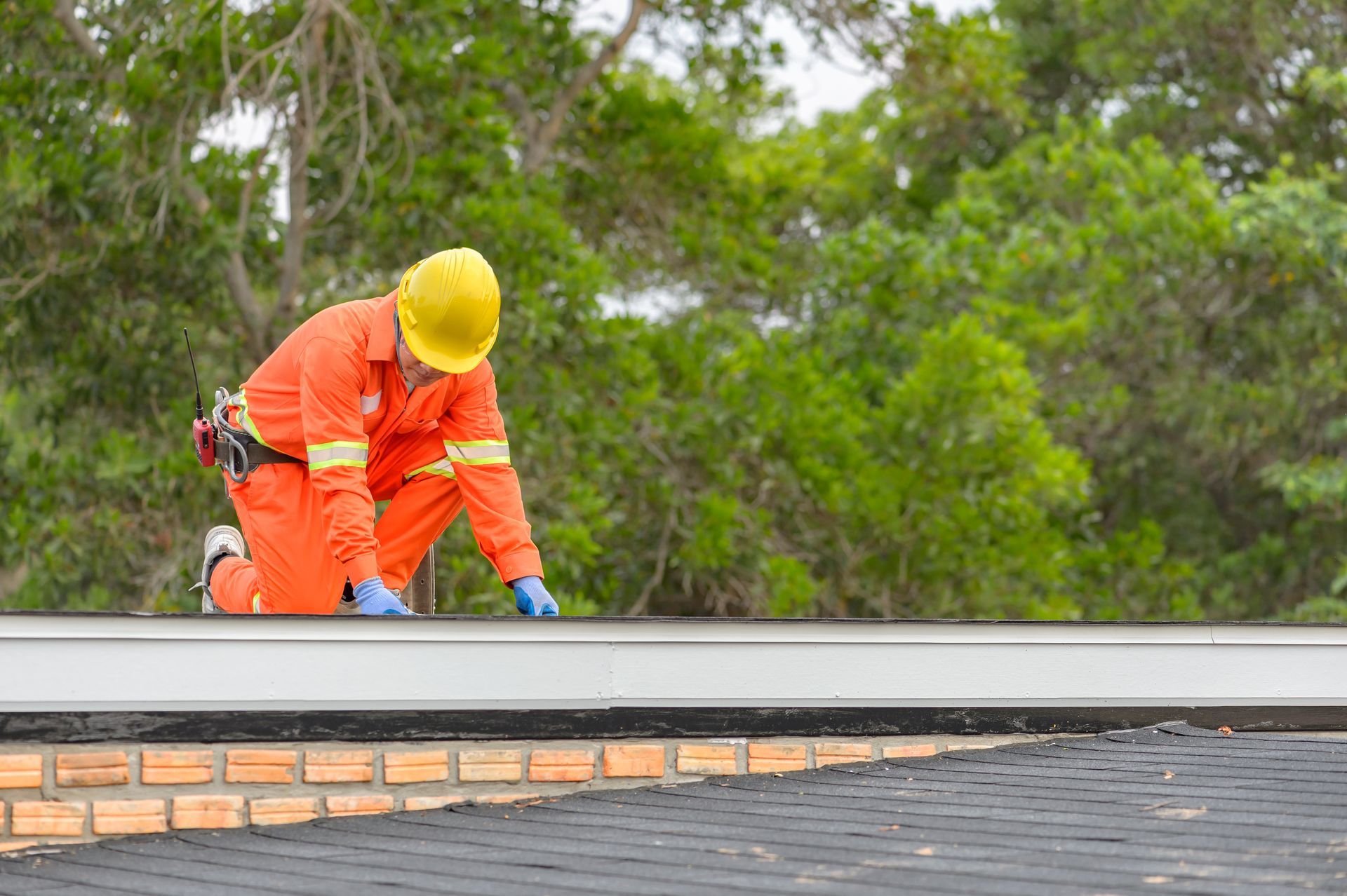 Worker in safety gear installing roofing material on a building. Worker in safety gear installing roofing material on a building.