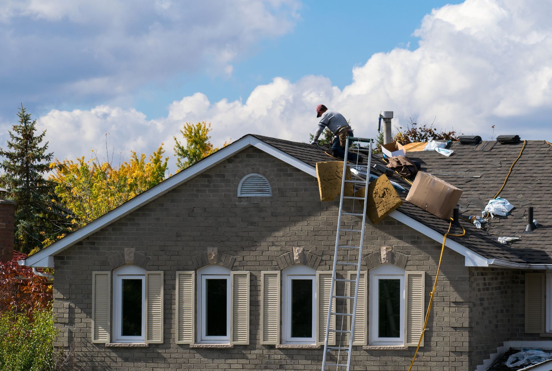 Professional contractor performing emergency roofing repairs on a damaged residential shingle roof. Professional contractor performing emergency roofing repairs on a damaged residential shingle roof.