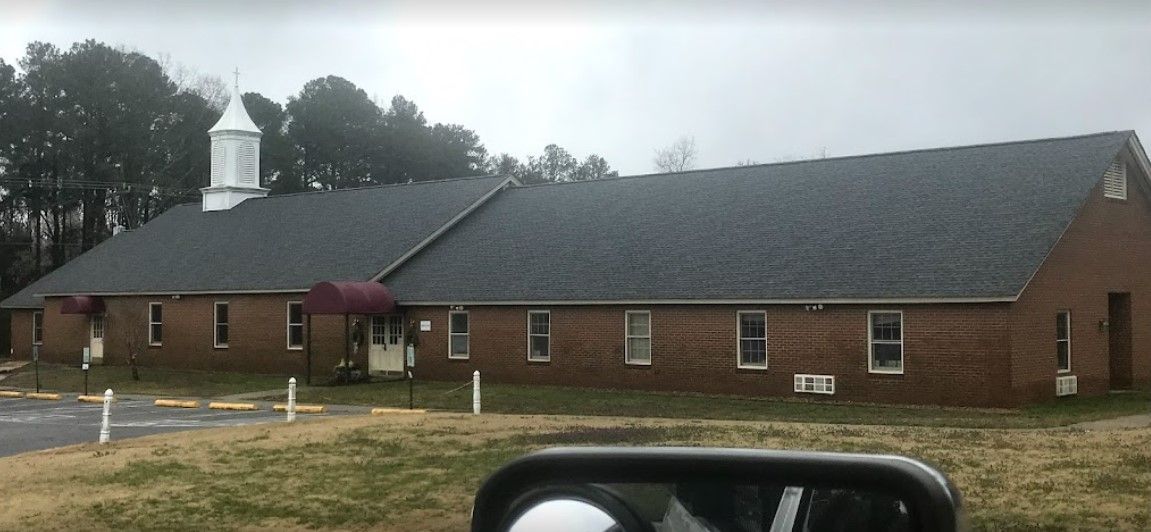 A brick church with a gray roof is visible in a rear view mirror.