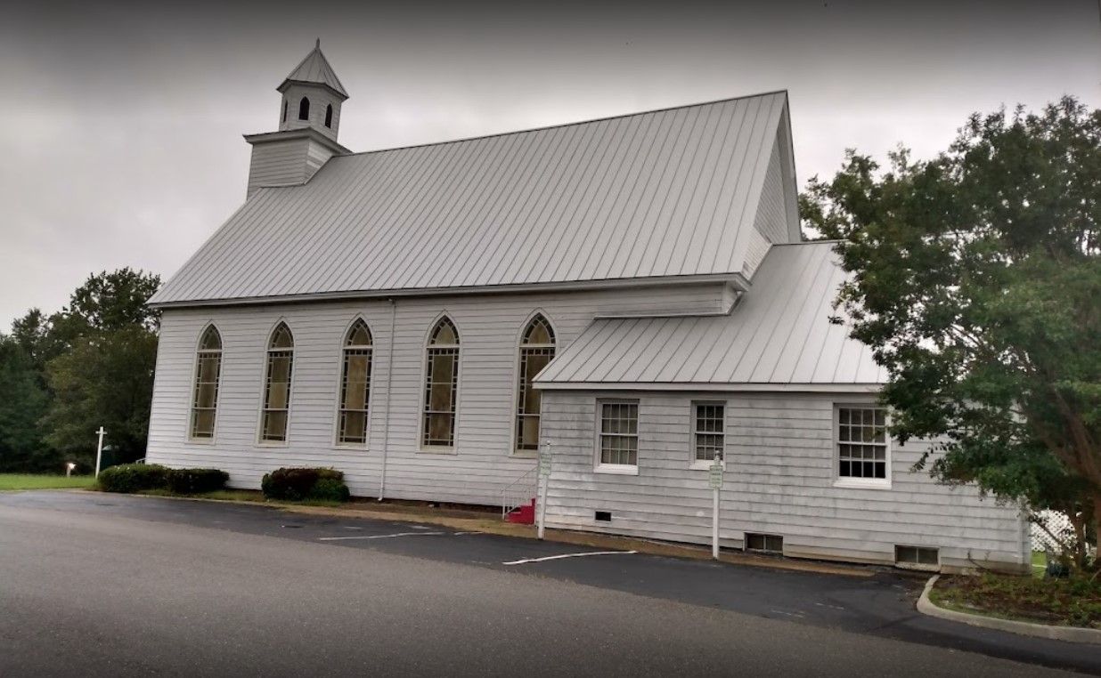 A white church with a metal roof and a steeple
