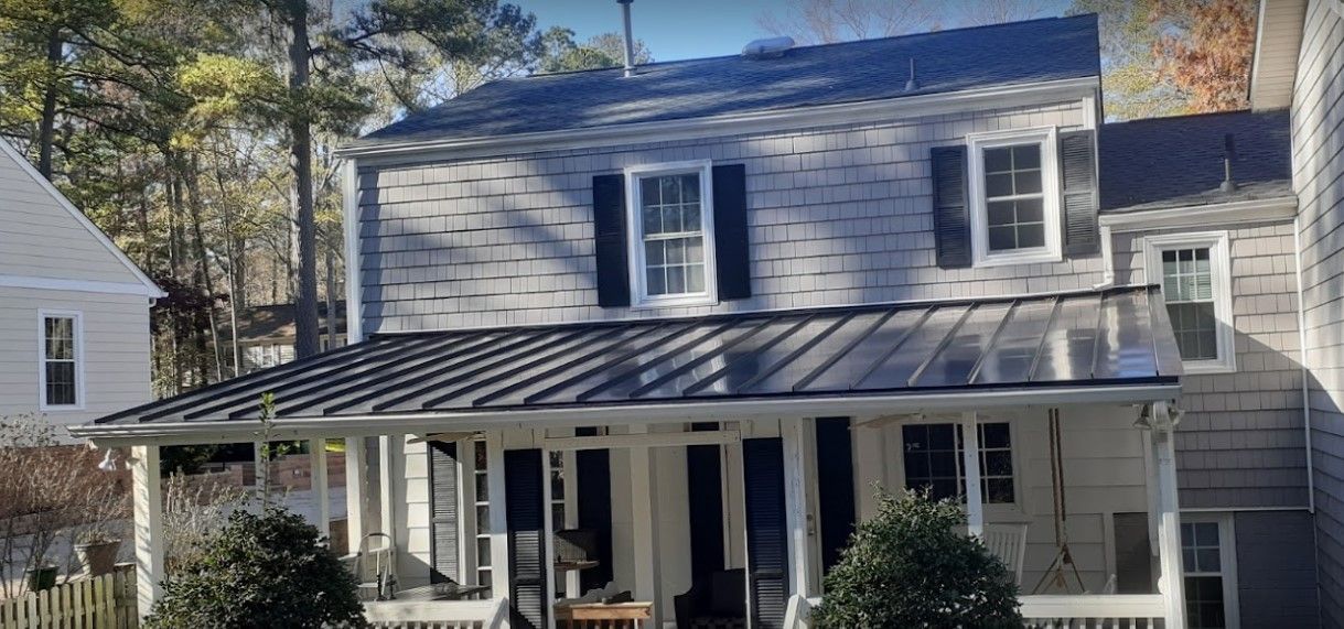 A white house with a black roof and a porch.