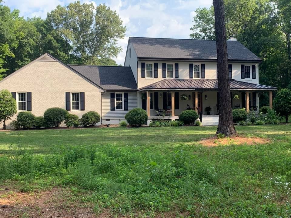 A large house with a porch and a large lawn in front of it.