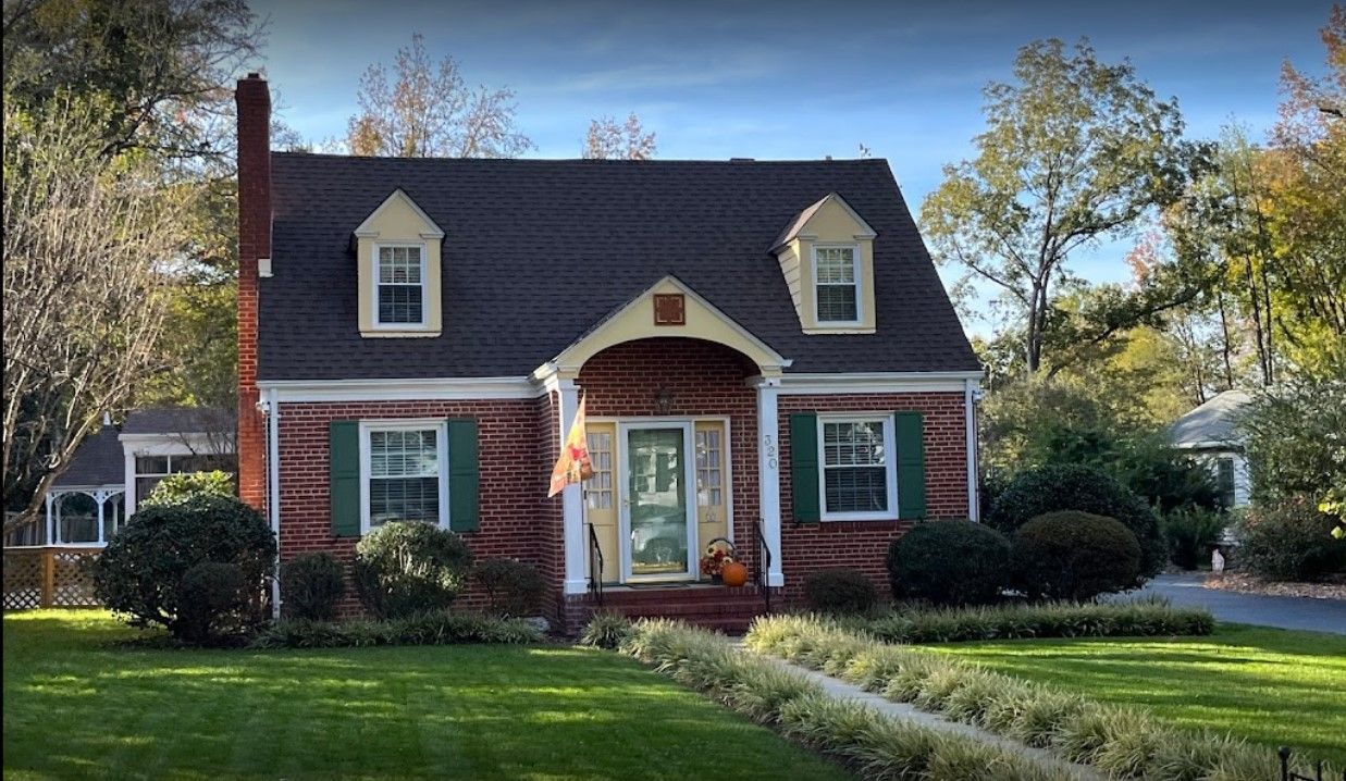 A brick house with a black roof and green shutters
