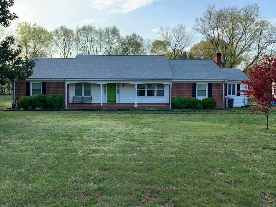 A brick house with a gray roof and a green door