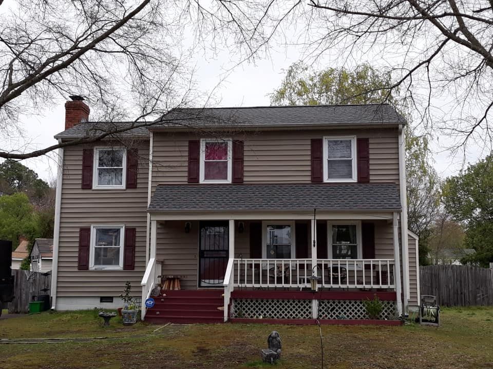 A large house with a large porch and a gray roof.