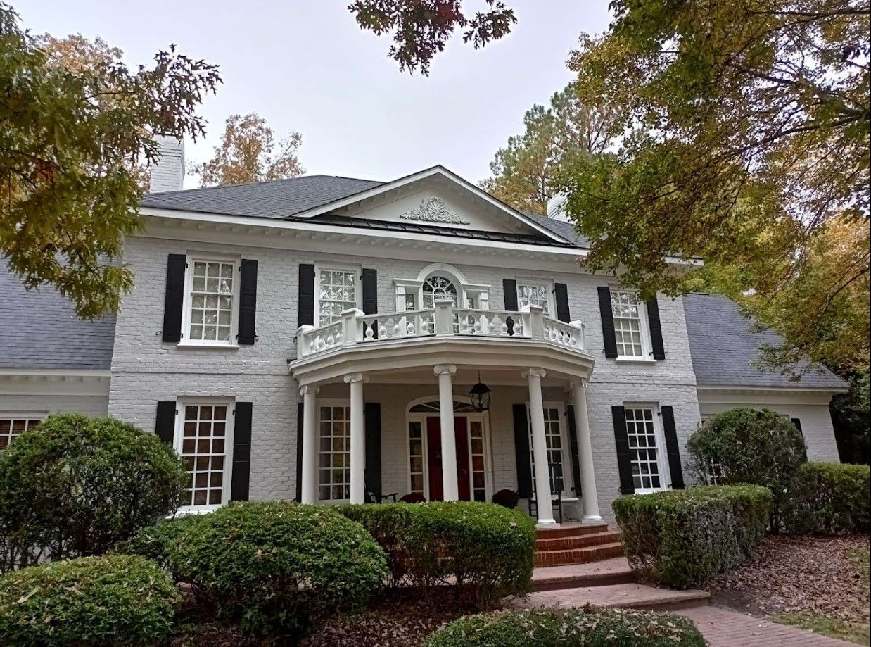 A large white brick house with black shutters on the windows
