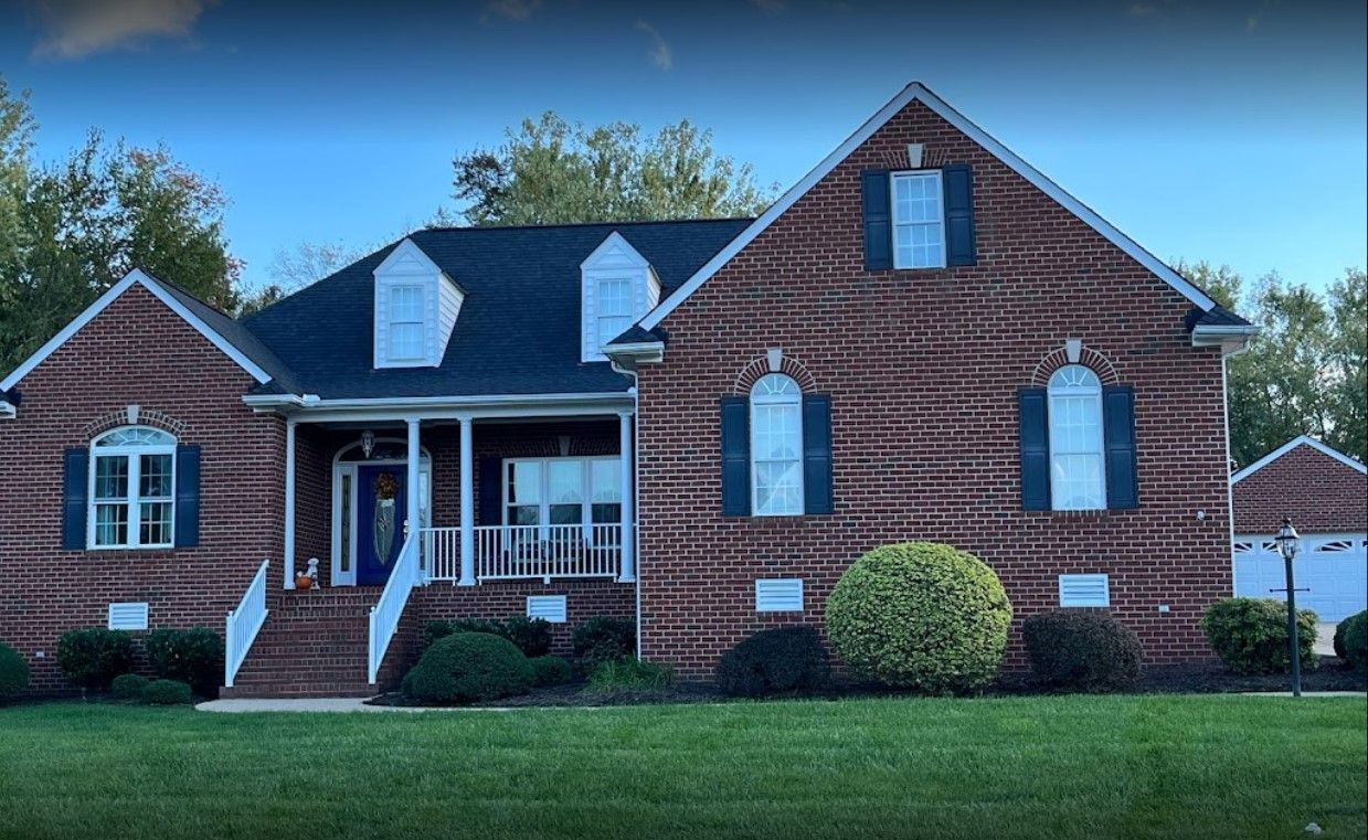 A large brick house with a blue roof and black shutters
