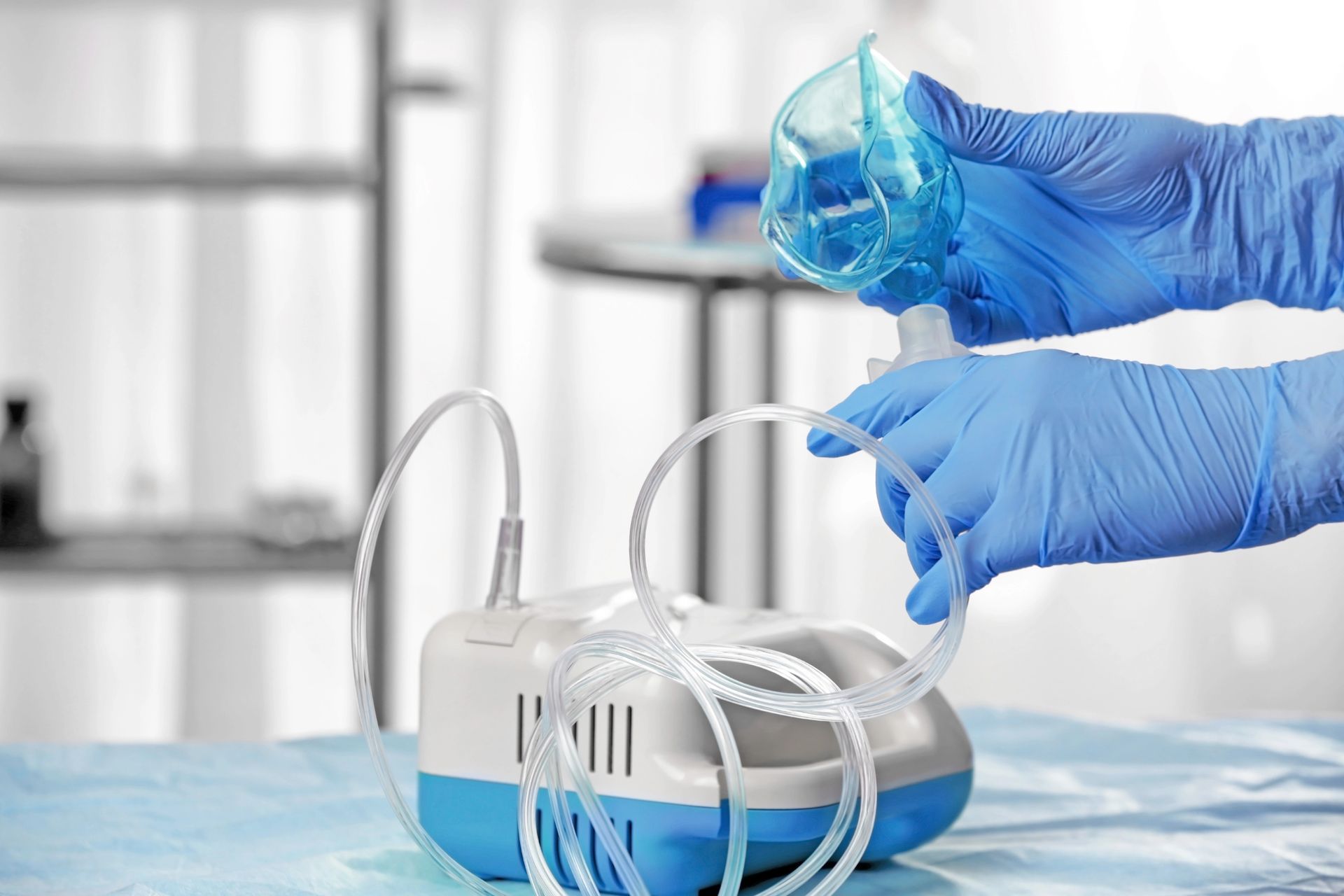 Manos enguantadas montando una mascarilla de oxígeno transparente sobre una cama de hospital