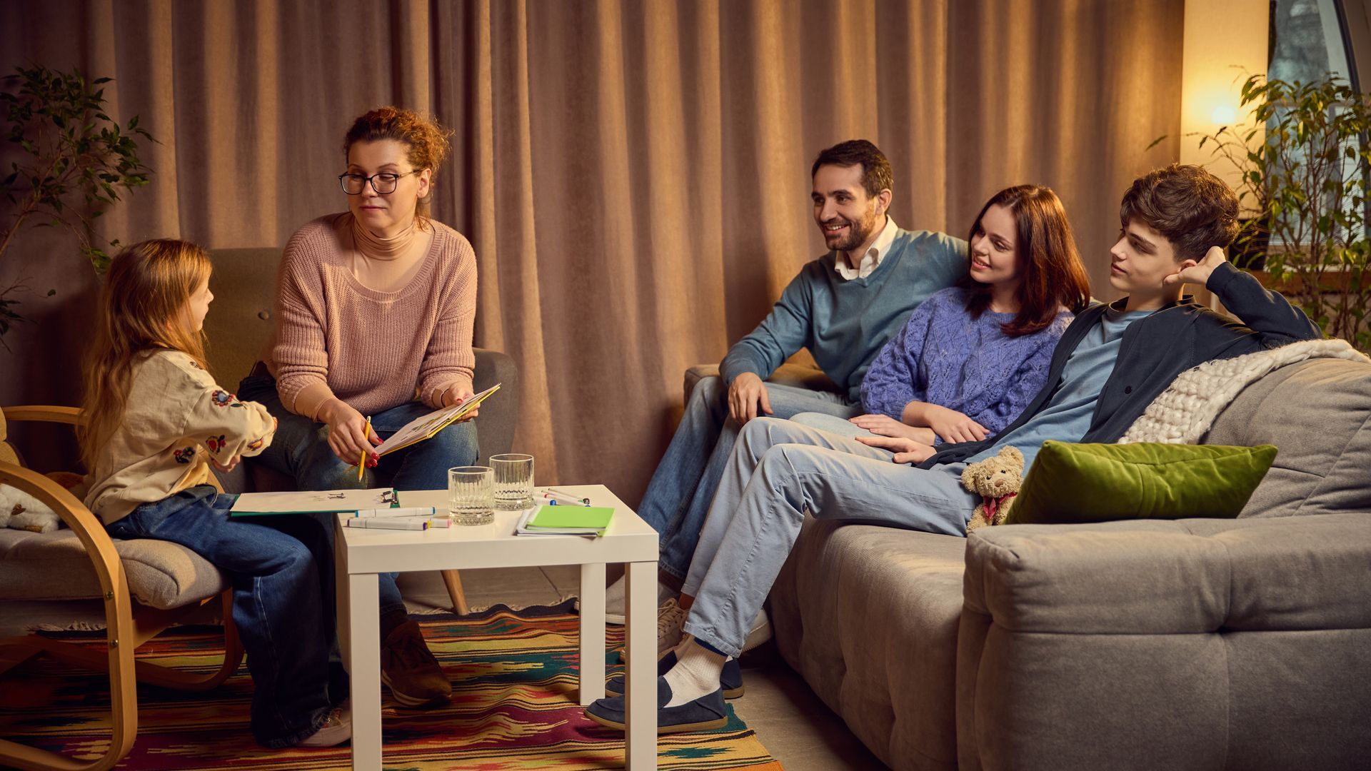 A family is sitting on a couch in a living room talking to each other.