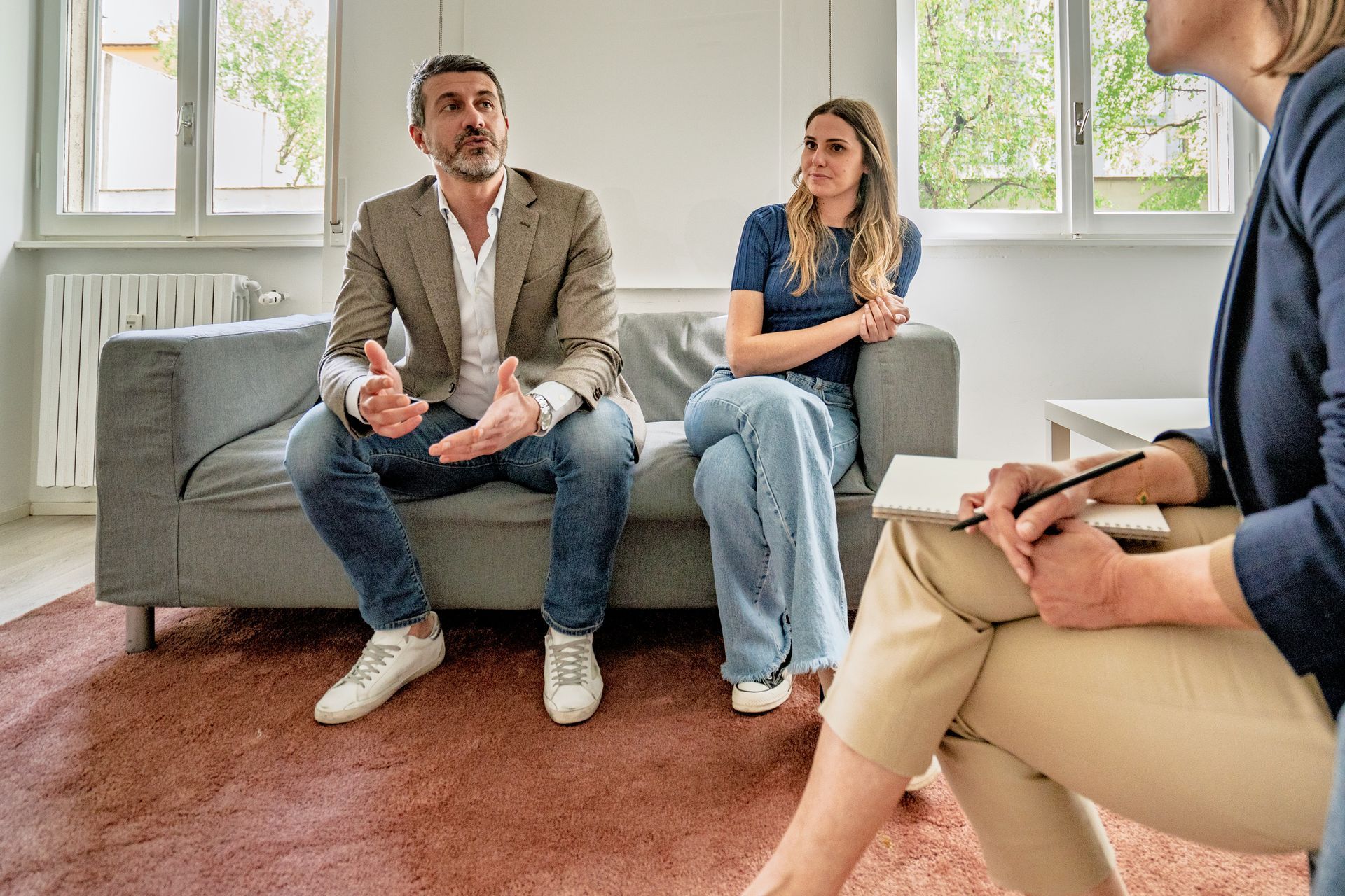 A man and a woman are sitting on a couch talking to a woman.