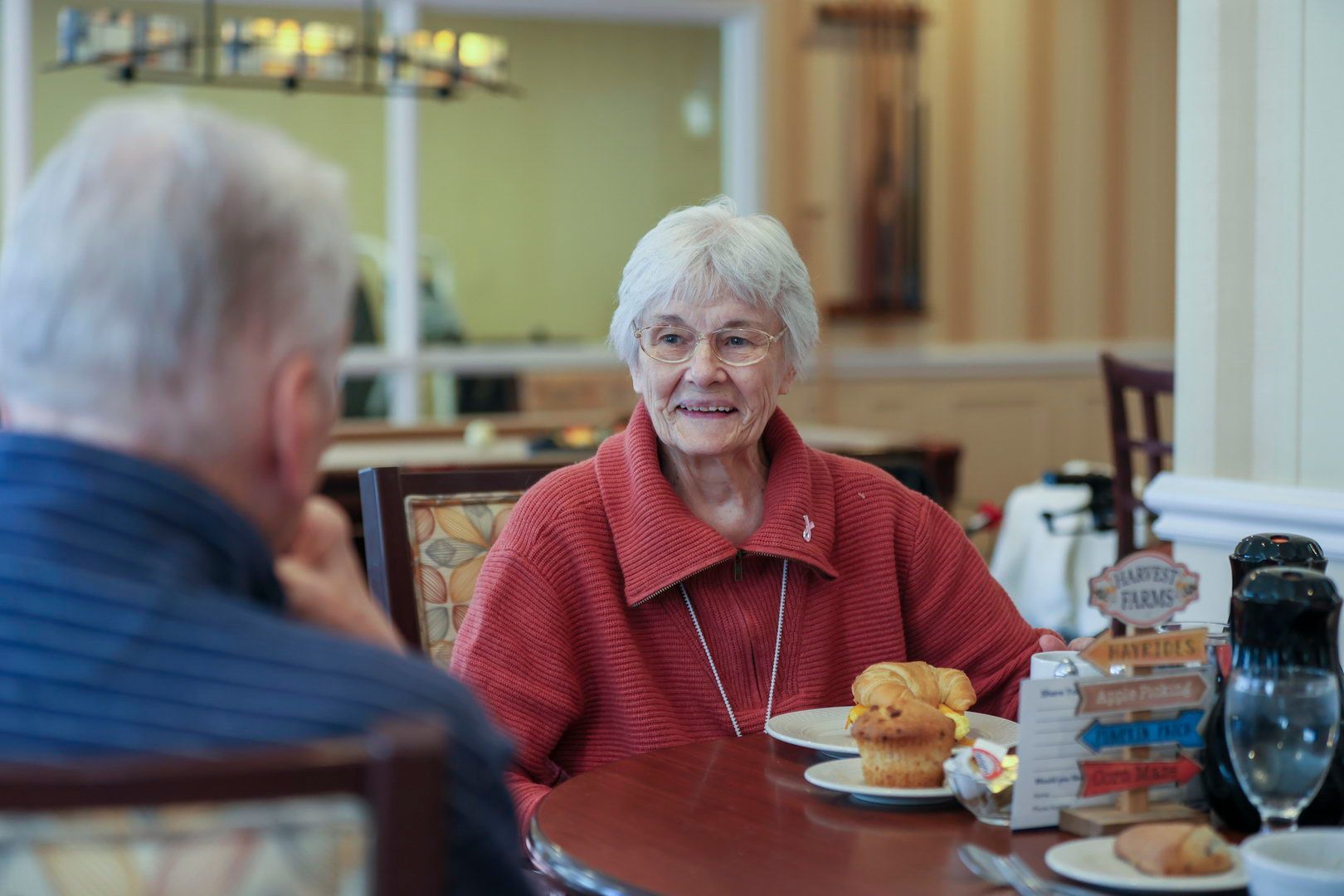 Smiling caregiver sitting beside elderly male resident in wheelchair