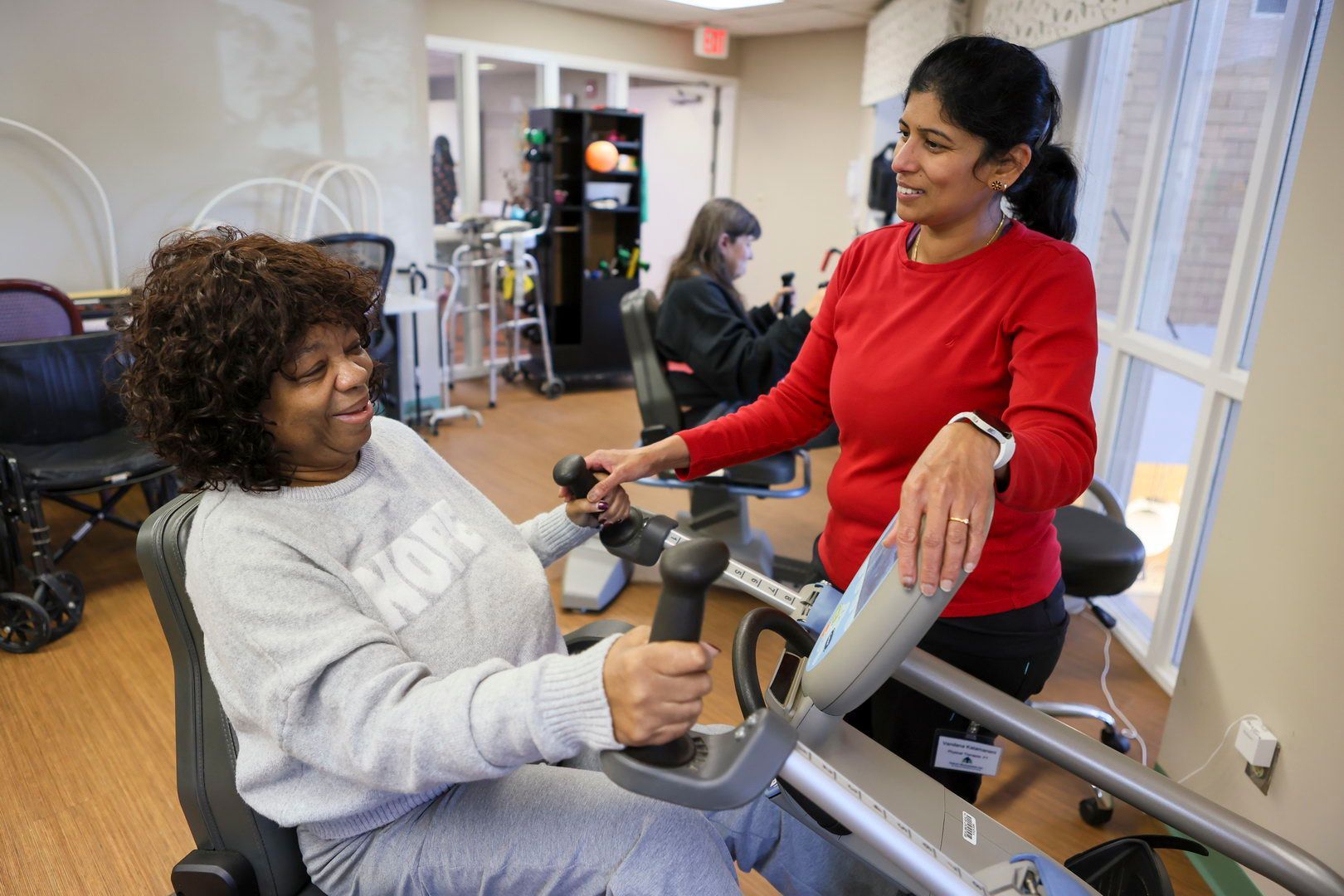 Smiling nurse with clipboard consulting with elderly patient at Riverside Commons skilled nursing center