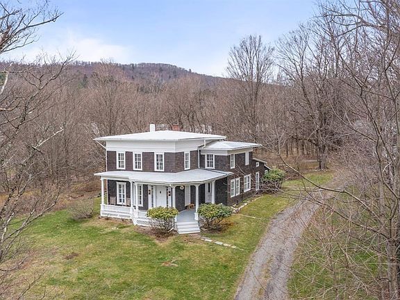 An aerial view of a large house in the middle of a forest.