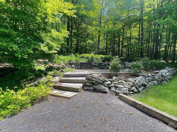 A path leading to a stone wall in the middle of a forest.
