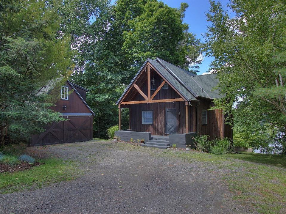 A small wooden house with a green roof is surrounded by trees