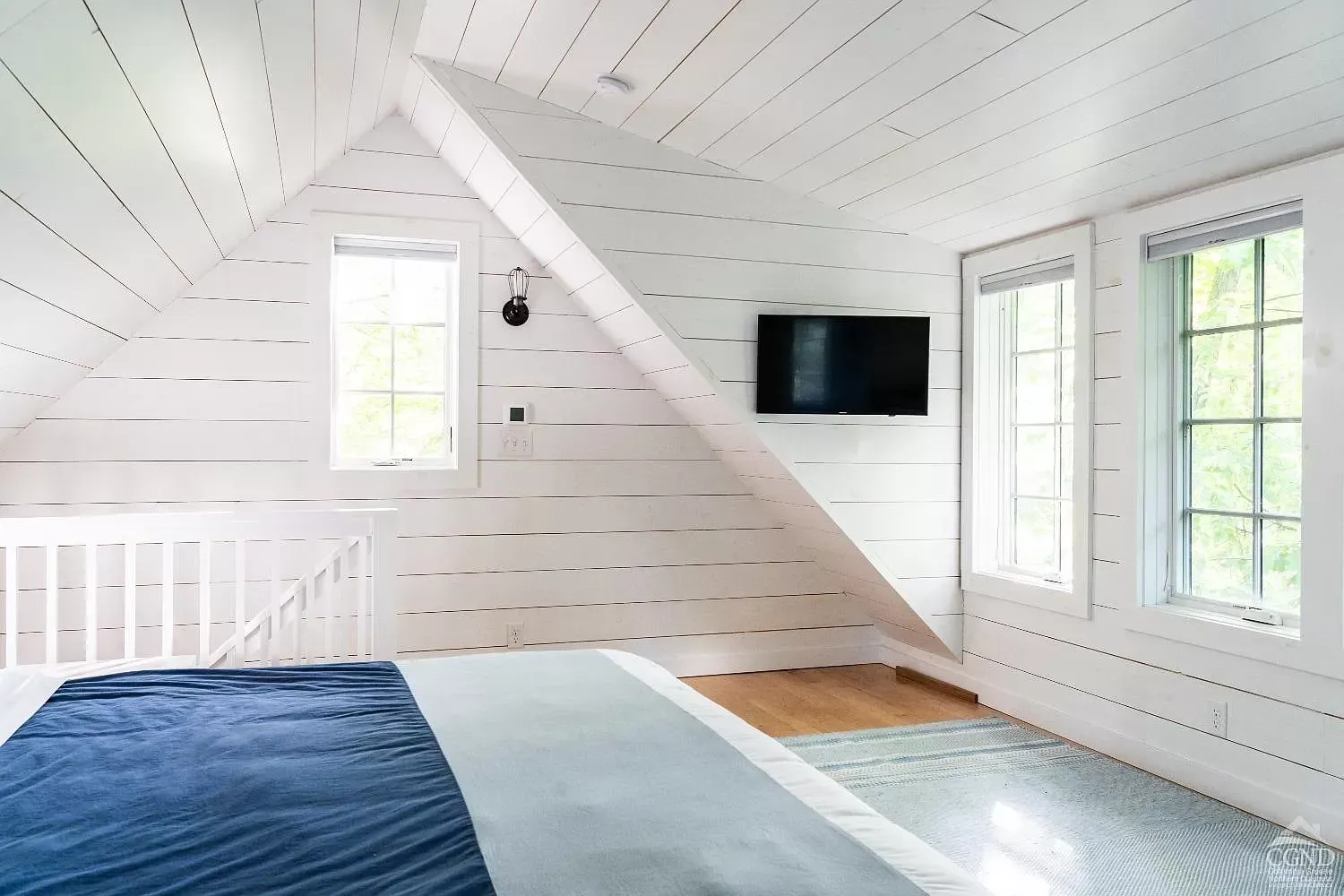 A bedroom with a bed and a television on the wall.