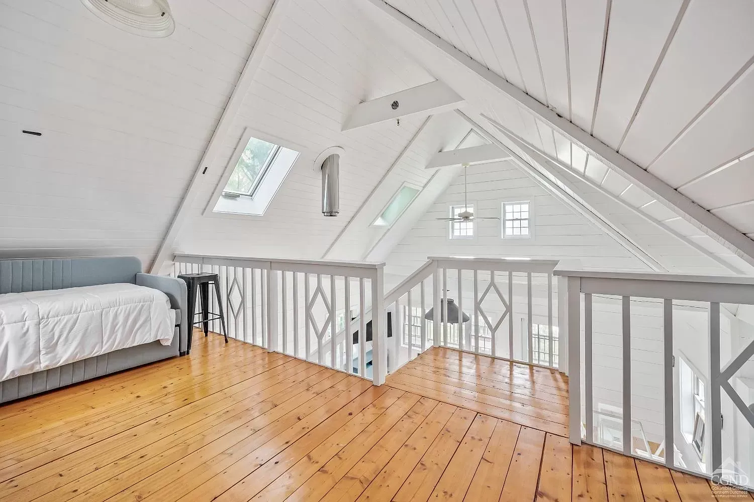 There is a couch in the attic with a wooden floor.