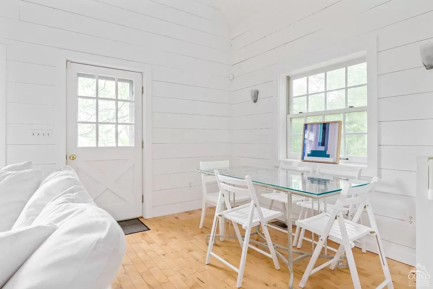 A living room with a glass table and chairs and a white couch.