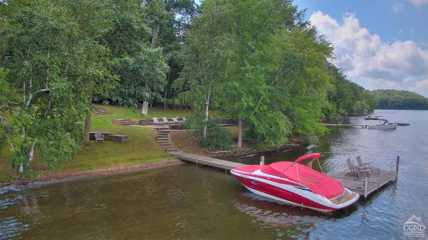 An aerial view of a red boat docked at a dock on a lake.