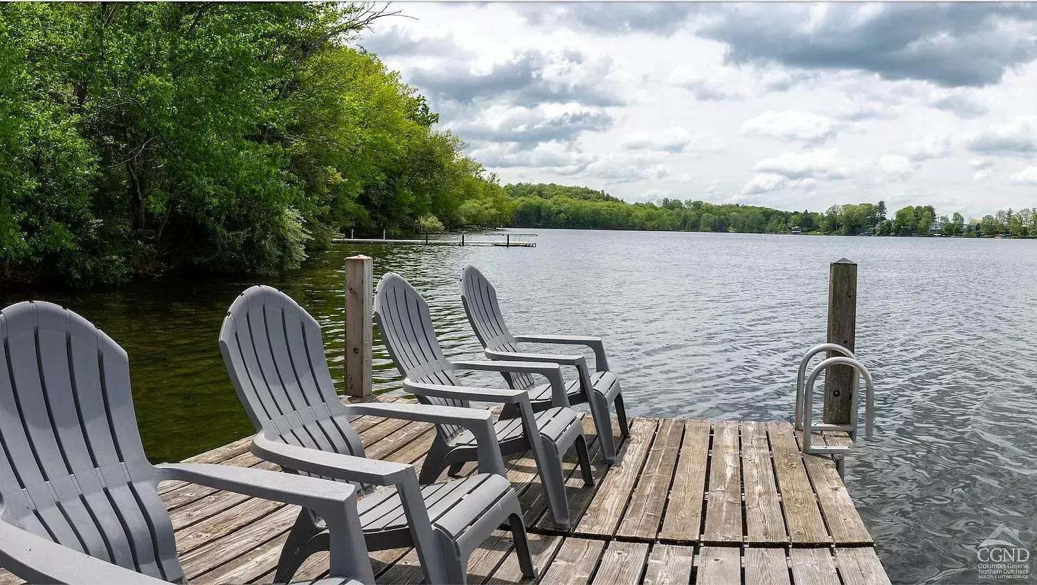 A row of chairs on a dock overlooking a lake
