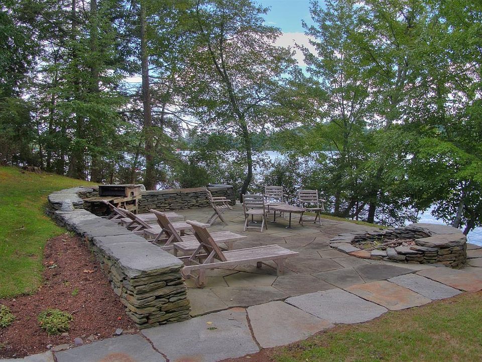 A patio with a fire pit and chairs next to a lake.