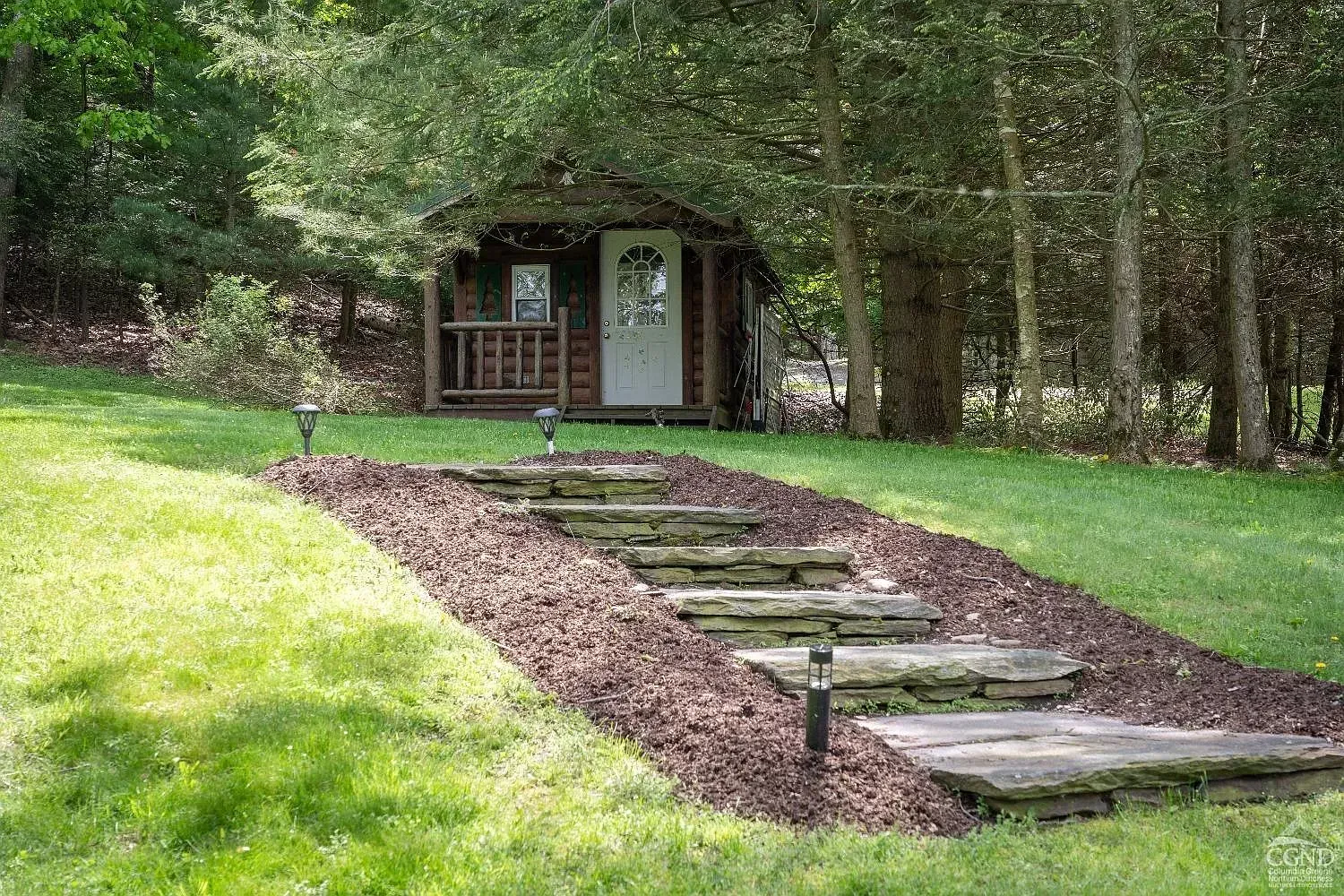 A path leading to a shed in the middle of a lush green field.