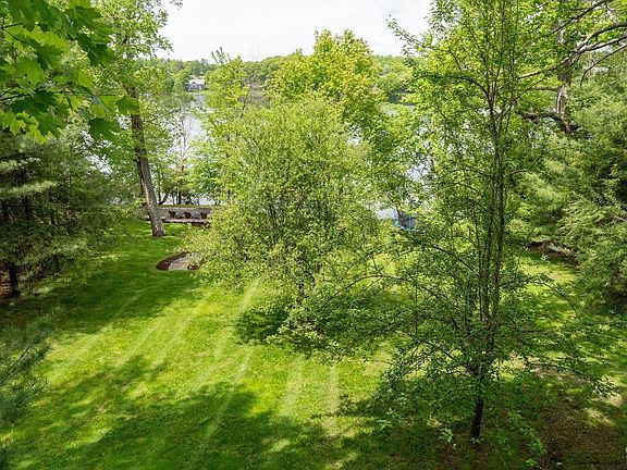 An aerial view of a lush green yard with trees and a lake in the background.