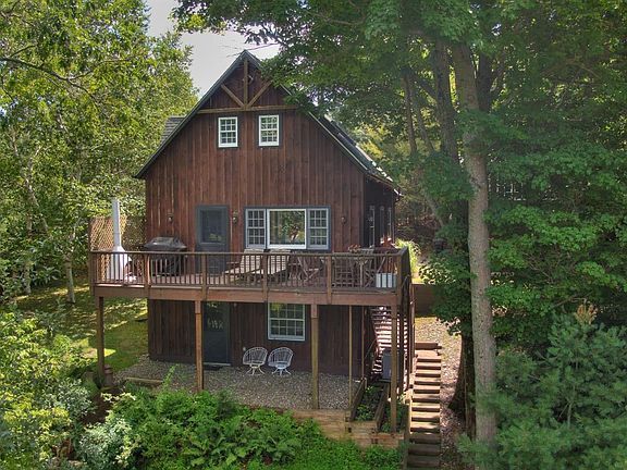 An aerial view of a wooden house with a large deck surrounded by trees.