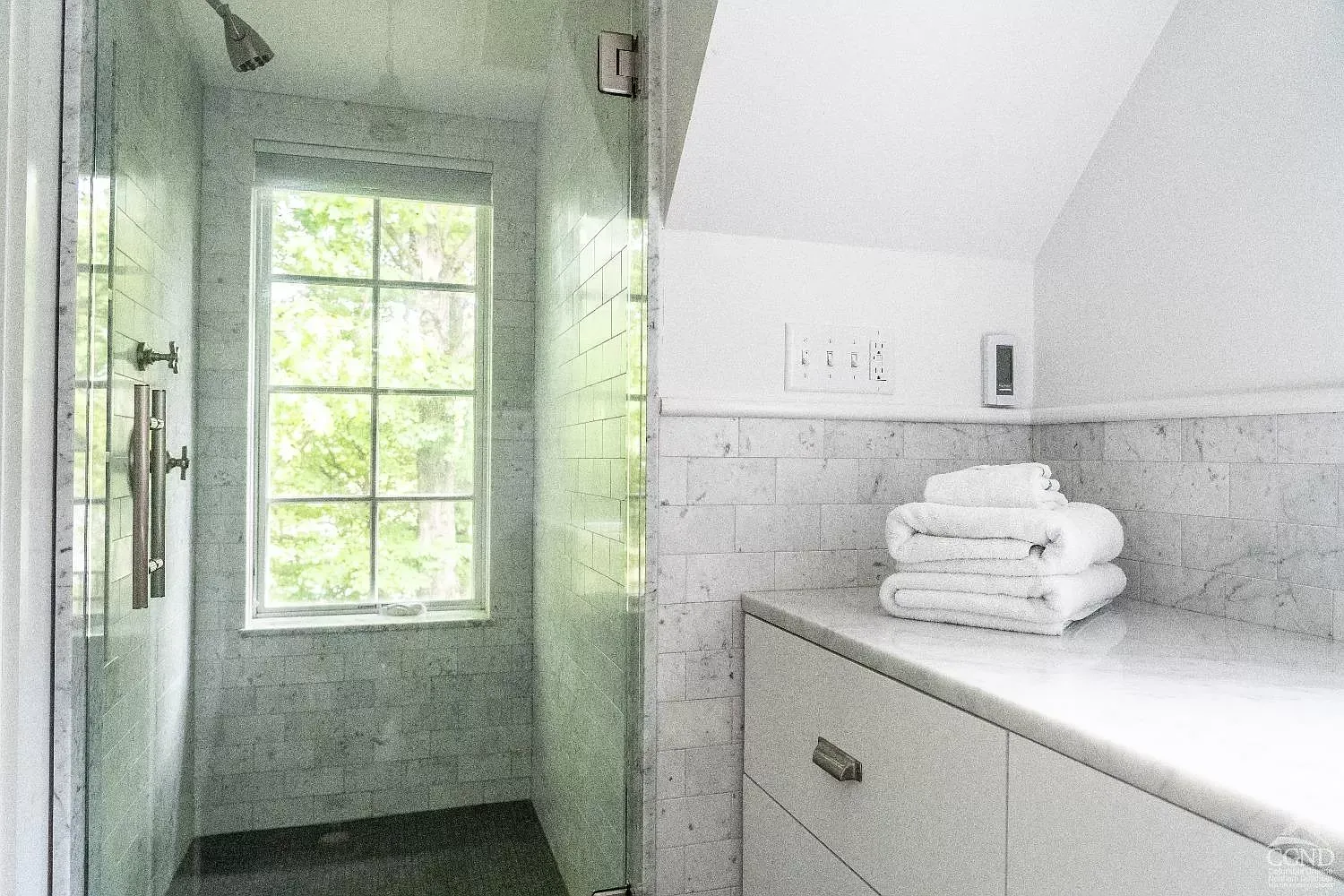 A bathroom with a walk in shower and a window.