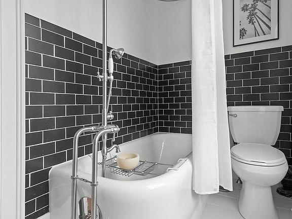 A bathroom with a bathtub , toilet and shower.
