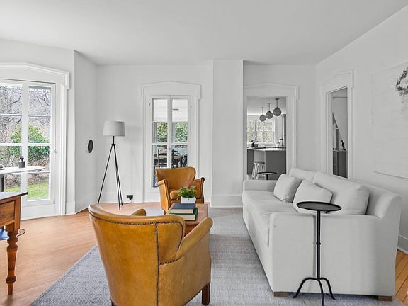 A living room with a white couch , chairs , and a desk.