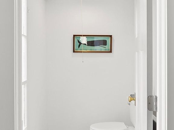 There is a picture of a whale on the wall above the toilet.
