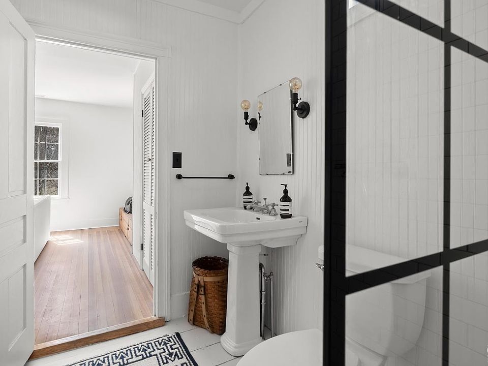 A bathroom with a sink , toilet , mirror and walk in shower.