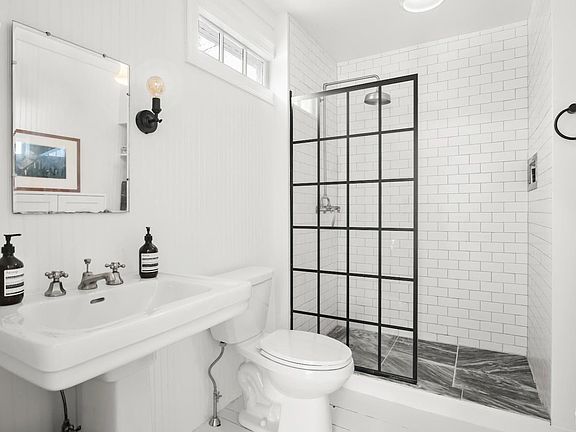 A bathroom with a toilet , sink , shower and mirror.