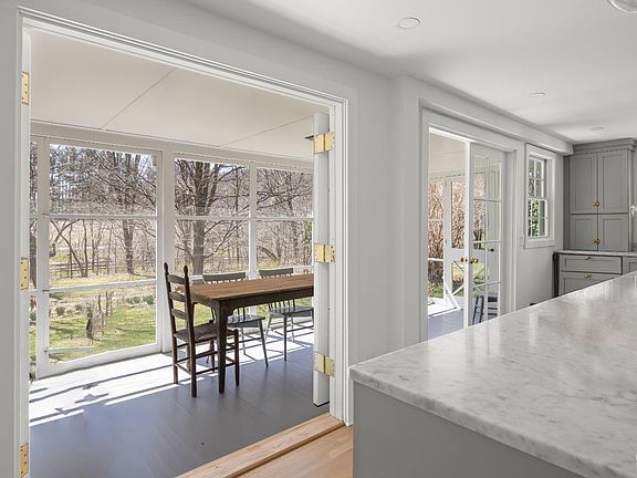 A dining room with a table and chairs and a kitchen with sliding glass doors.
