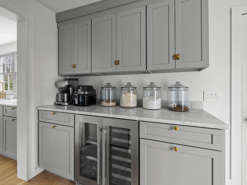 A kitchen with gray cabinets and a stainless steel refrigerator.