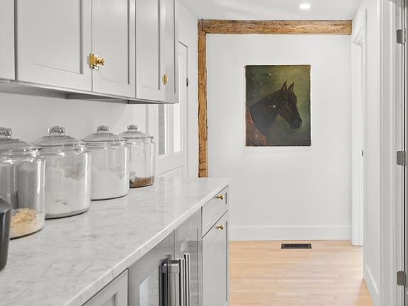 A kitchen with white cabinets and a painting of a horse on the wall.