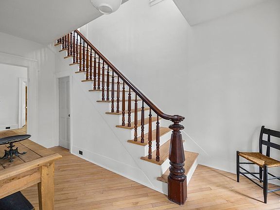 A wooden staircase with a wooden railing in a room with a table and chairs.