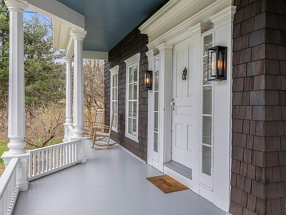 A porch with a rocking chair and a welcome mat on it.